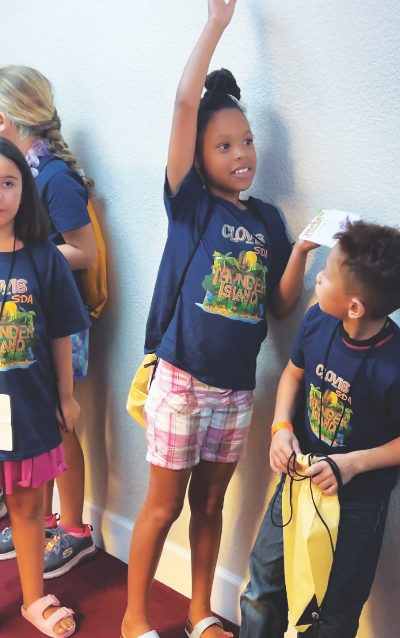 Una niña en Clovis levanta la mano queriendo ser elegida para compartir el punto de la Biblia.
